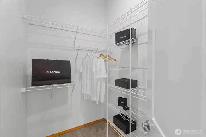 Walk-in closet with built-in wire shelving and hanging space for organized storage. Carpeted flooring and multiple shelves provide room for clothing and accessories.