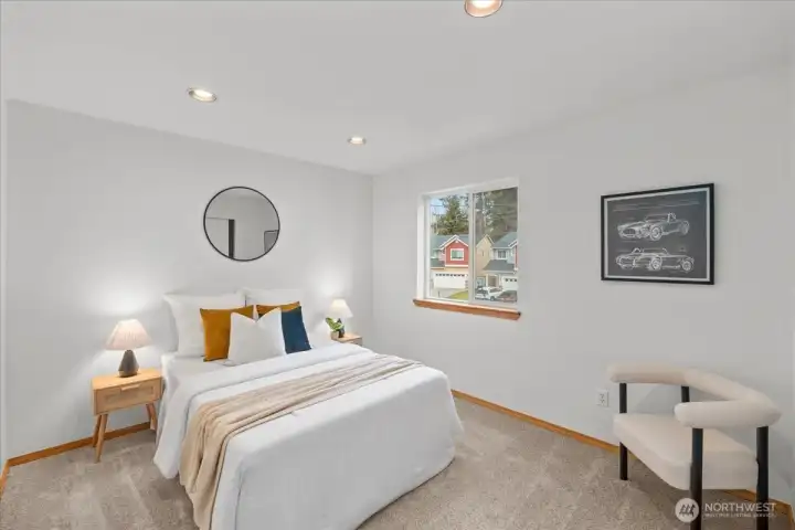 Bedroom with neutral finishes, recessed lighting, and a window overlooking the neighborhood. Carpeted flooring adds comfort.