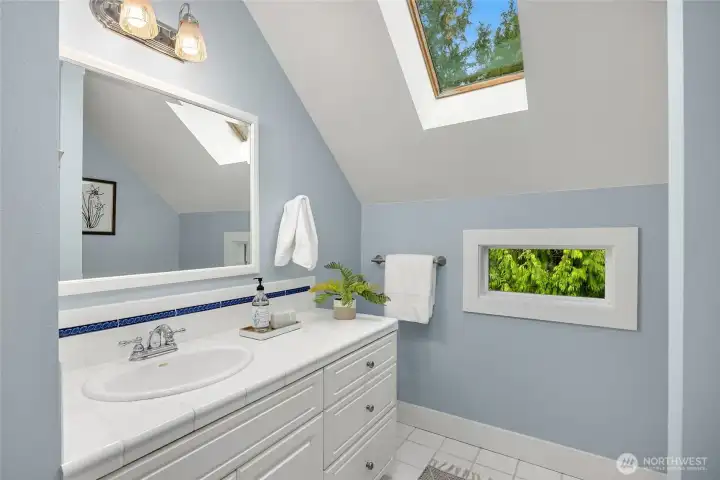 The upper bathroom includes a large vanity and skylight.