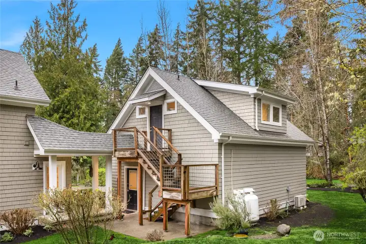 The side door to the laundry room is connected to the detached garage by a covered walkway. Exterior steps lead to the separate space over the garage.