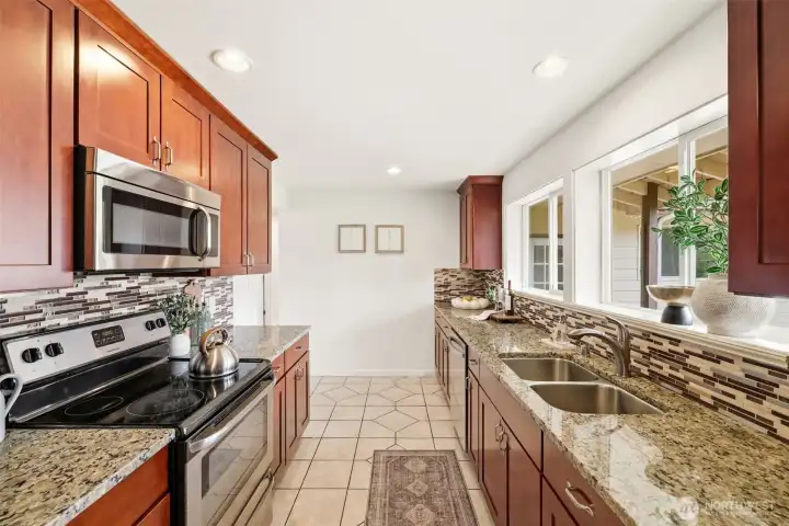 Well-appointed kitchen with tile floors, slab counters, and abundant cabinetry