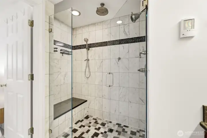 Marble step-in shower with glass enclosure in primary bath