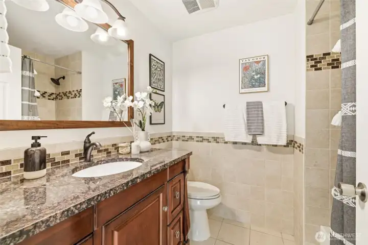 Hall full bath with granite vanity and tile surround