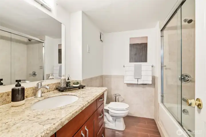 Lower level full bath with granite vanity and glass-enclosed tub and shower