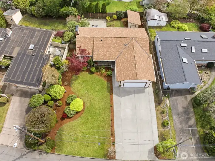 Aerial view showcasing spacious lot, wide driveway, and mature landscaping