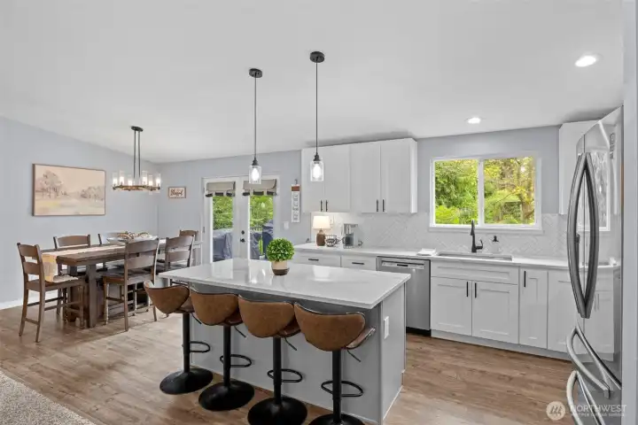 Kitchen boasts stylish quartz counter tops accented by black hardware and deco tile back splash.