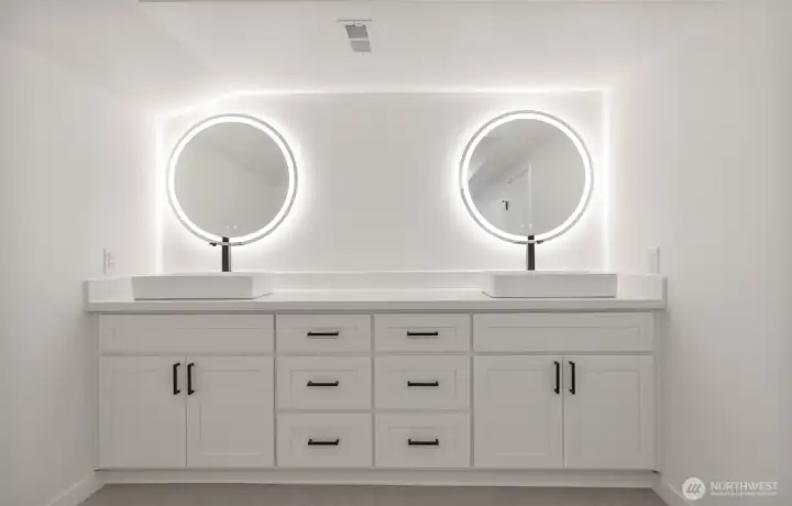Primary bathroom w/ dual vessel sinks w/ individual storage, each paired with lighted vanity mirror