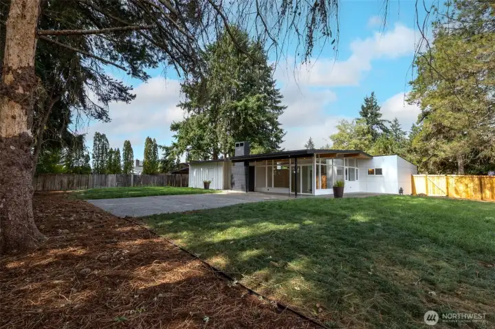 Spacious elevated backyard featuring grass, paved entertainment areas, and unobstructed sky, partial mountain and territorial views