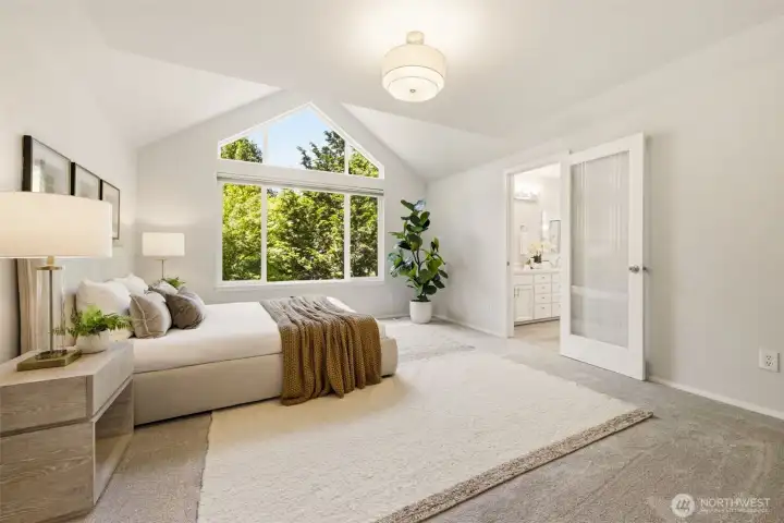 Welcome to your primary retreat featuring vaulted ceilings, tons of natural light from the large window, and french doors Welcome to your primary retreat featuring vaulted ceilings, tons of natural light from the large window, and french doors