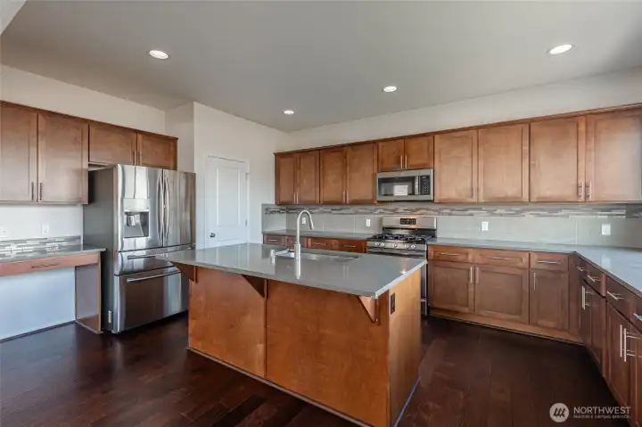 Central granite island with sink and eating bar. Walk-in pantry keeps essentials organized and accessible. Planning desk provides dedicated workspace.