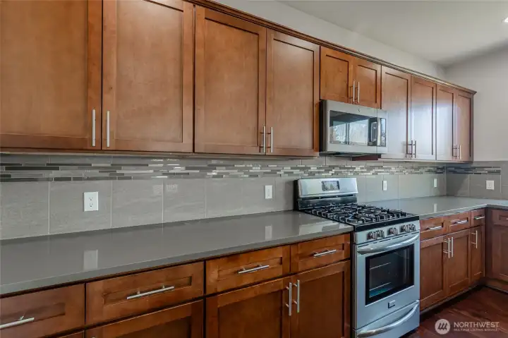 Full-height backsplash adds style and durability. Soft-close cabinets provide functional storage. Stainless steel appliances designed for modern living.