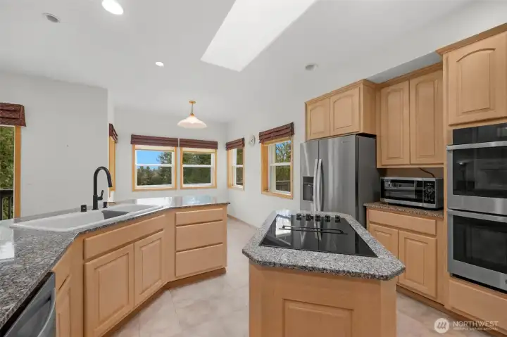 This kitchen has tile floors, granite counters,double ovens, a pantry, island, maple cabinetsn with pullout drawers and a wet bar.