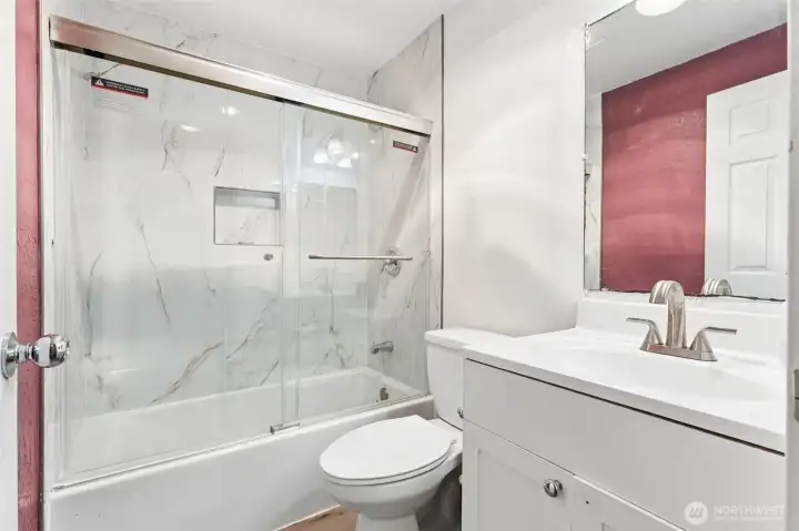 Updated bathroom featuring a modern vanity, brushed nickel fixtures, tub/shower with elegant surround and sliding glass doors. Updated bathroom featuring a modern vanity, brushed nickel fixtures, tub/shower with elegant surround and sliding glass doors.