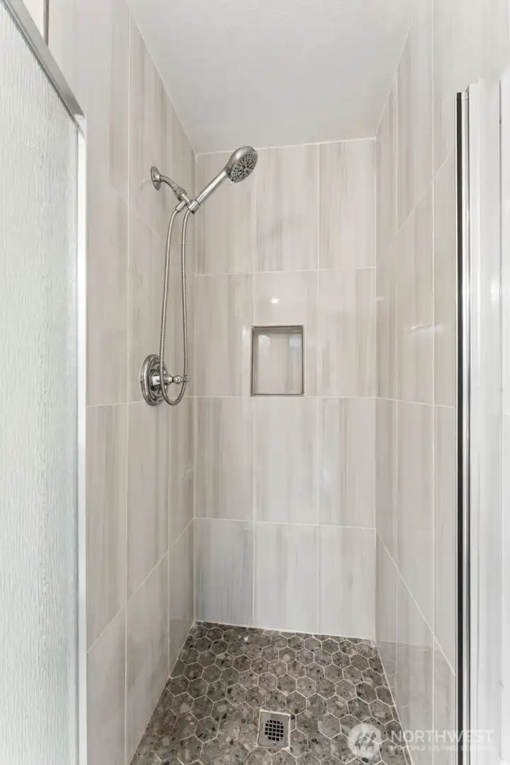 Second bathroom features a beautifully updated walk-in shower showcases contemporary floor-to-ceiling tile, a built-in shampoo niche, elegant pebble-style flooring, and modern fixtures. Second bathroom features a beautifully updated walk-in shower showcases contemporary floor-to-ceiling tile, a built-in shampoo niche, elegant pebble-style flooring, and modern fixtures.