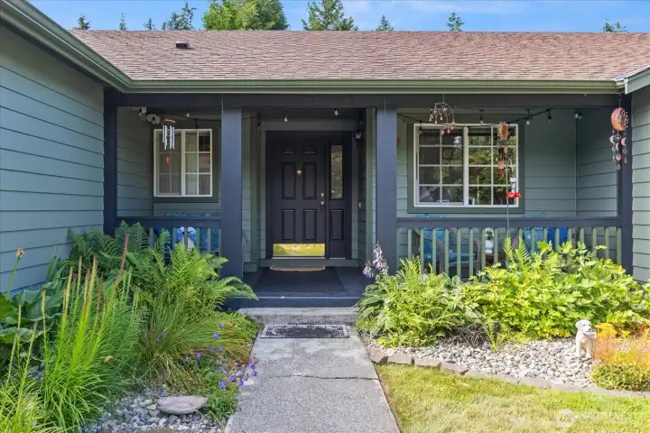 A welcoming covered entry is framed by mature landscaping, creating an inviting first impression.