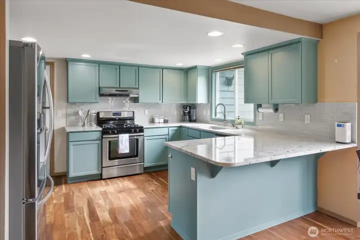 Quartz countertops, stainless steel appliances, designer tile backsplash, and an oversized peninsula create a kitchen that's as functional as it is beautiful.