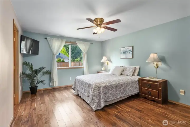 Spacious primary suite with hardwood floors, peaceful backyard views, and a calming retreat-like atmosphere.
