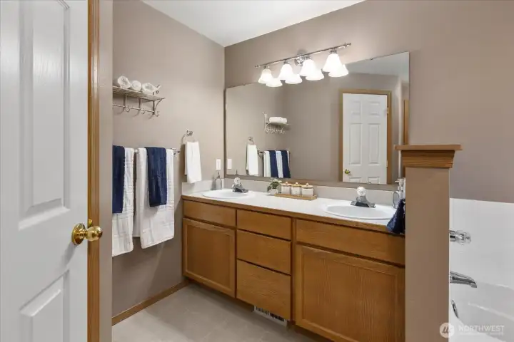 The primary bath features dual vanities, ample counter space, and convenient shared access to the soaking tub and shower.
