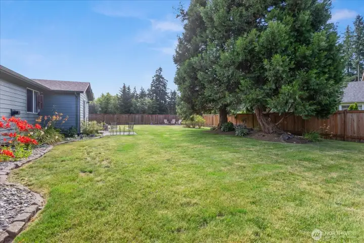 A spacious, fully fenced yard is complemented by mature trees and a dedicated fire pit area, creating a private outdoor retreat.