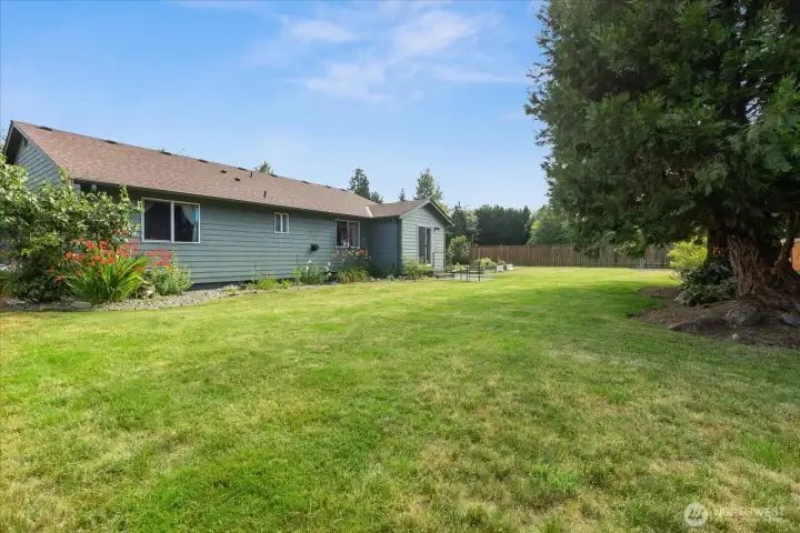 The backyard combines open lawn, established landscaping, and multiple outdoor seating areas, offering plenty of space to relax or entertain.