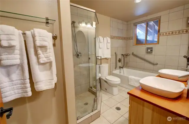 Full bathroom with deep soaker bathtub and glass tile shower.