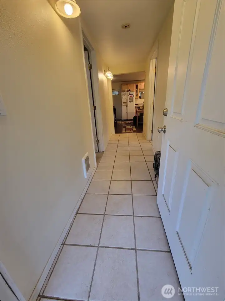 The kitchen with eating area & living room are at the end of the entry hallway. The laundry nook is behind the open door. One the left is the primary bedroom (being used as a home office) along with the primary bath. On the right side of the hallway is the second full bathroom.