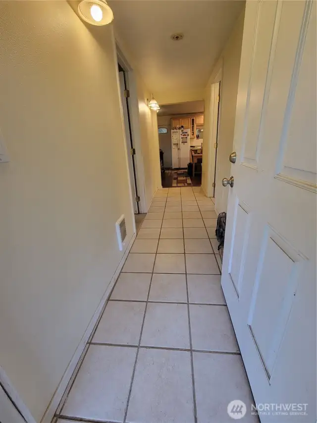The kitchen with eating area & living room are at the end of the entry hallway. The laundry nook is behind the open door. One the left is the primary bedroom (being used as a home office) along with the primary bath. On the right side of the hallway is the second full bathroom.
