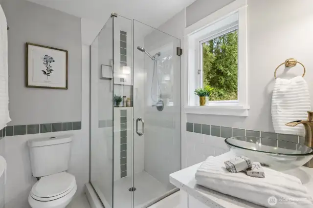 The 3/4 primary bath features updated tile flooring and shower as well as updated fixtures.