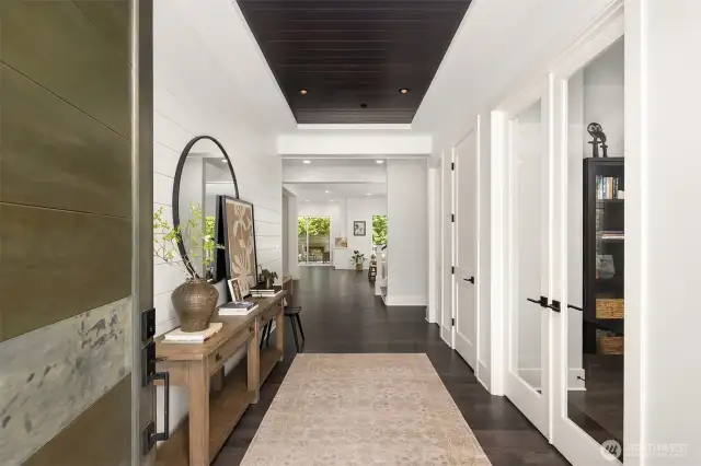 Upon arrival, commanding street presence yields to a thoughtfully curated interior featuring soaring ceilings, warm wide-plank hickory flooring, and distinctive shiplap accent walls.