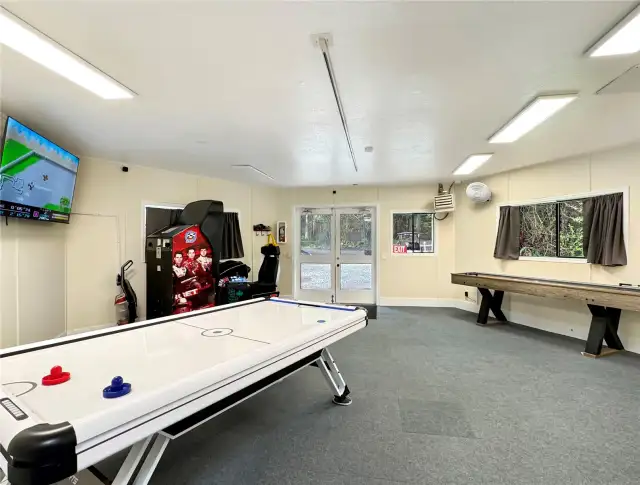 Rec room with air hockey, video games and shuffle board.