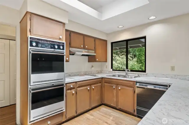 Original kitchen holds a lot of potential for expansion and updating! Nice and bright with layered ceilings and canned lights. To the left is the hallway that leads to a small deck and the original entry door.