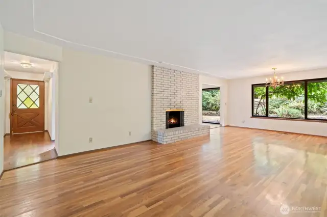 Living and dining area with view towards the private backyard - shows off the gleaming hardwoods without the virtual staging in place. Original front door to the left.