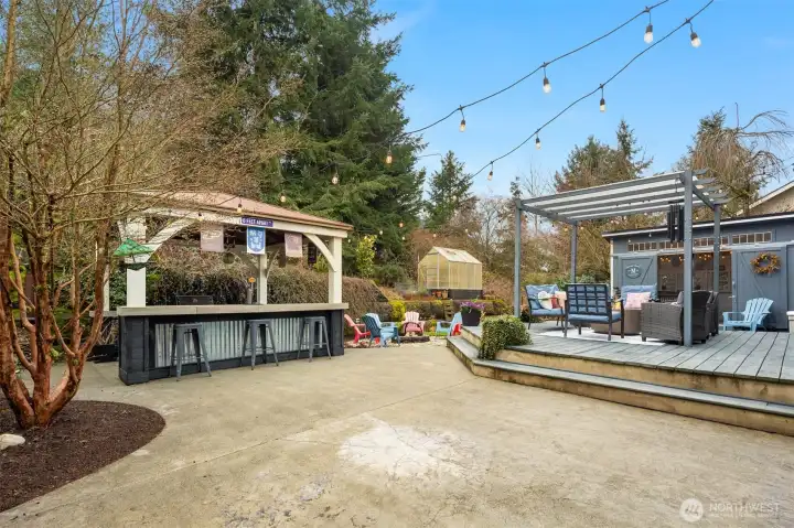 Spacious yard with deck, party cabana, greenhouse and outdoor dining room.