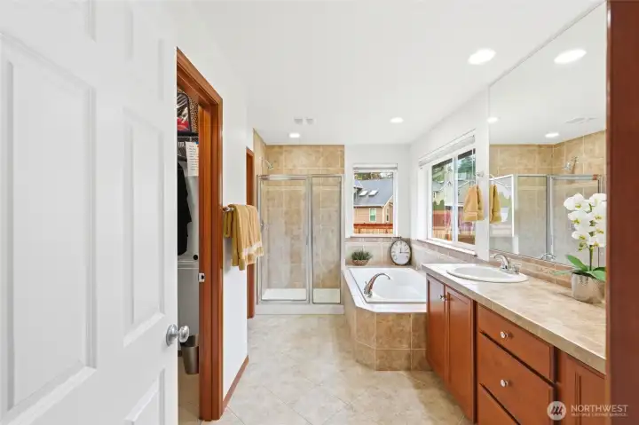 Primary en-suite bath with large soaking tub and walk-in shower is open and bright.