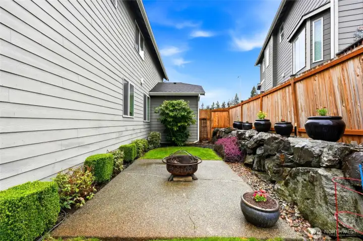 East side of the home has aggregate patio for easy maintenance plus flower pots that stay and garden space along the fence.