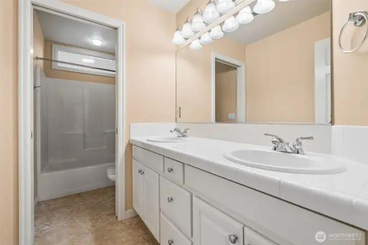 Guest bath features a water closet and double vanity sinks