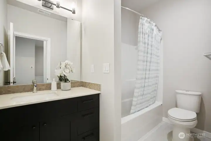 Picture of the the secondary bath off the hall with a nice size tub, elevated cabinets and quartz countertops.