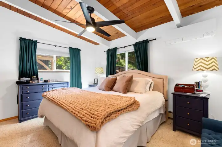 Primary bedroom features a minisplit and ceiling fan for comfort, and windows that face the backyard decks. Primary bedroom features a minisplit and ceiling fan for comfort, and windows that face the backyard decks.