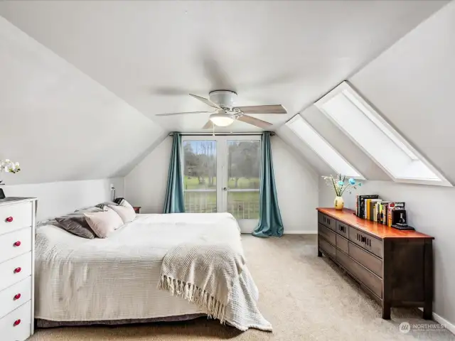 Primary bedroom with skylights & french doors that overlook property