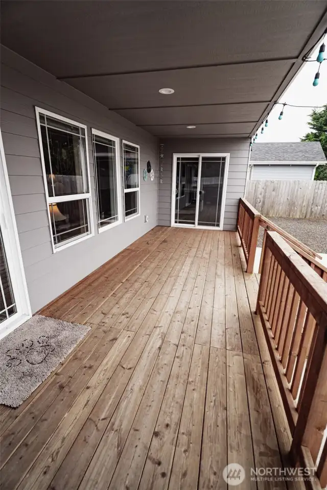 A very large covered deck. Door on the left is the sliding door that goes into the living room. Door straight ahead goes into the primary bedroom.