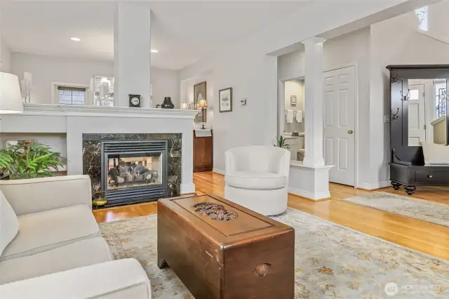 Living room, area rug, hardwood floors, gas fireplace, view to entry, hallway to 3/4 bath, bedroom, den, or office.