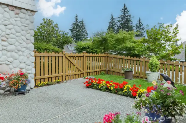 Stone wall and fence borders patio, green space for the owner's pup to romp (a little) on nice days.  Black bird watches over all.