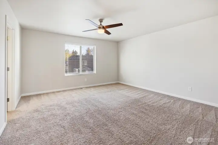 Sunlit primary bedroom complete with ceiling fan for comfort