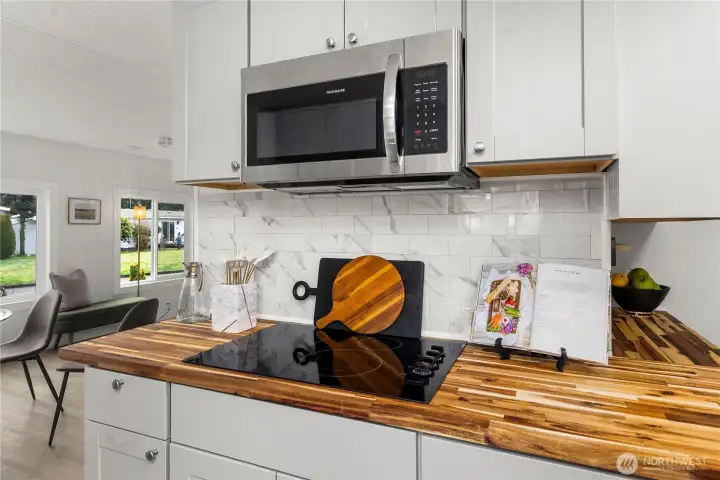 NEW glass-top range paired with a NEW stainless steel microwave & NEW backsplash adds modern style and everyday functionality to this beautifully updated kitchen.