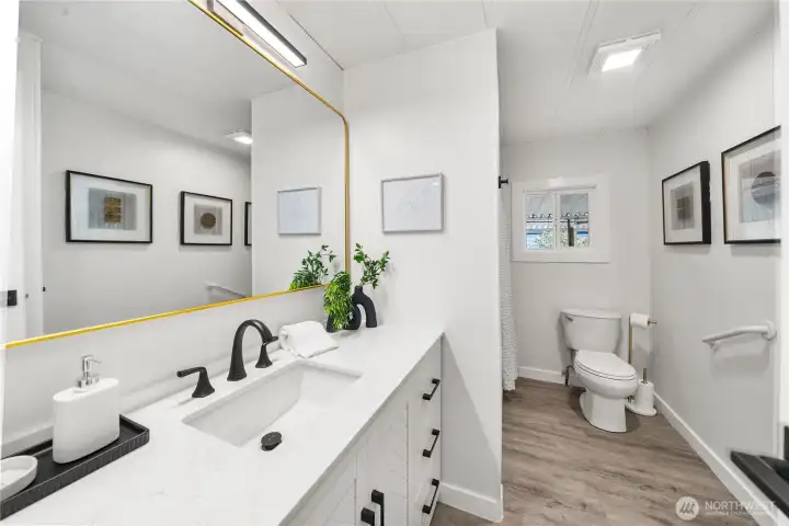 Guest bathroom features a NEW vanity with abundant counter and storage space, NEW LVP flooring, plus a NEW mirror and lighting for a bright, updated look.