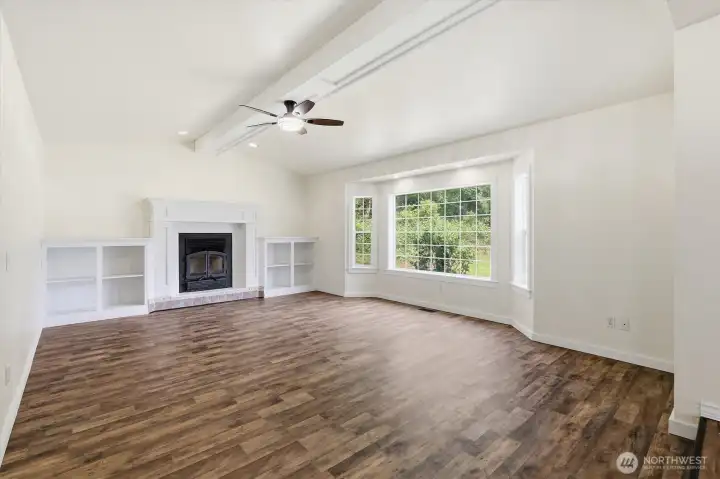 Large living room with ceiling fan, vaulted ceilings, large windows and wood fireplace