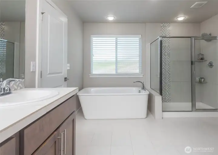 The spa-inspired ensuite features a stunning freestanding soaking tub and a beautifully appointed glass-enclosed shower.