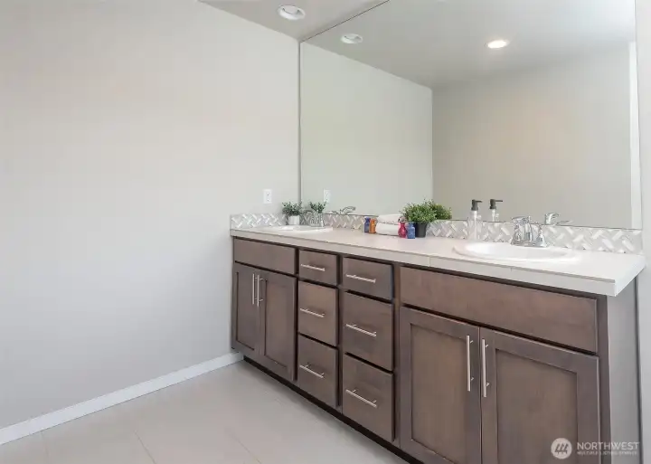 The five-piece primary bathroom offers a well-appointed layout, complemented by an oversized mirror that amplifies light and adds to the room’s expansive feel.