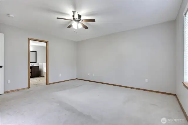 Large primary suite with ceiling fan.