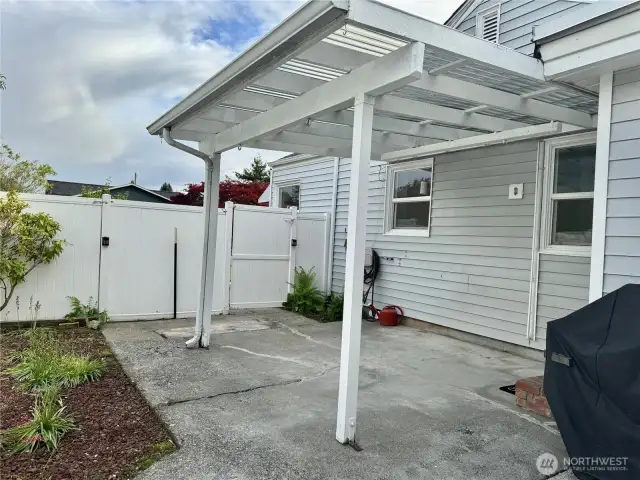 Covered patio, completely fenced with vinyl fencing.